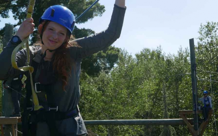 a student smiles while participating in a ropes course with outward bound
